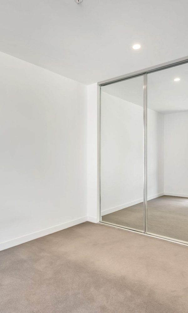 An empty room with the windows' reflection in the mirrored closet